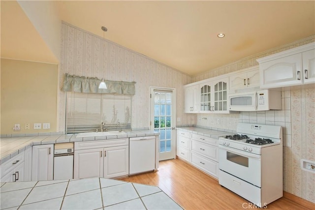 kitchen with tile counters, white cabinets, and white appliances