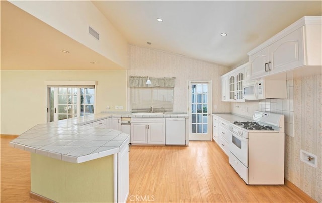 kitchen featuring kitchen peninsula, white appliances, white cabinets, light hardwood / wood-style floors, and tile counters