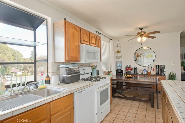 kitchen with decorative backsplash, white appliances, crown molding, sink, and tile counters