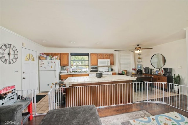 kitchen with ceiling fan, tile countertops, crown molding, white appliances, and hardwood / wood-style flooring