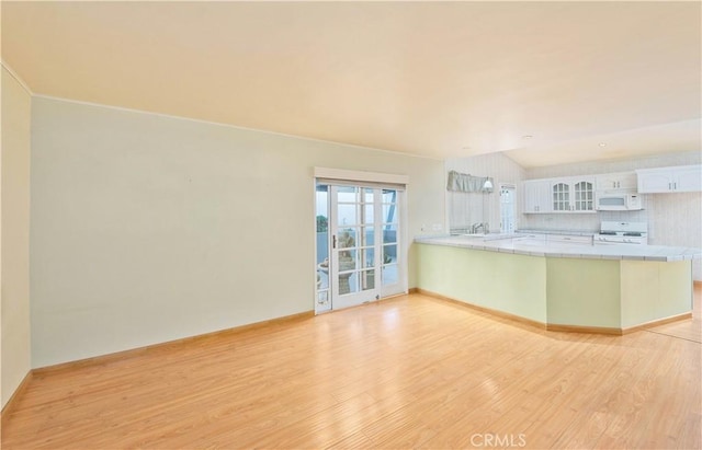 kitchen with tile countertops, white appliances, white cabinets, light wood-type flooring, and kitchen peninsula