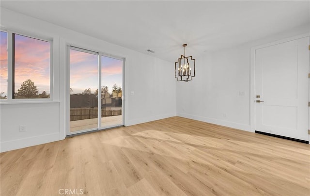 spare room featuring an inviting chandelier and light hardwood / wood-style floors