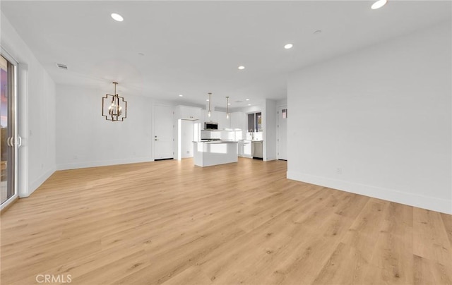 unfurnished living room featuring light hardwood / wood-style flooring and a chandelier