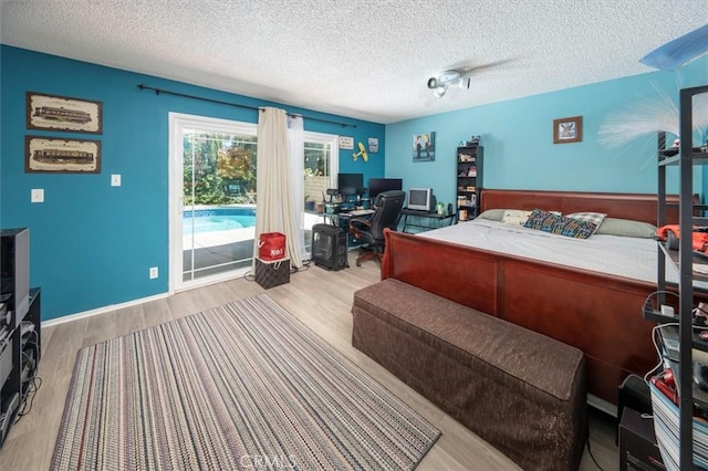 bedroom with access to outside, a textured ceiling, and light wood-type flooring