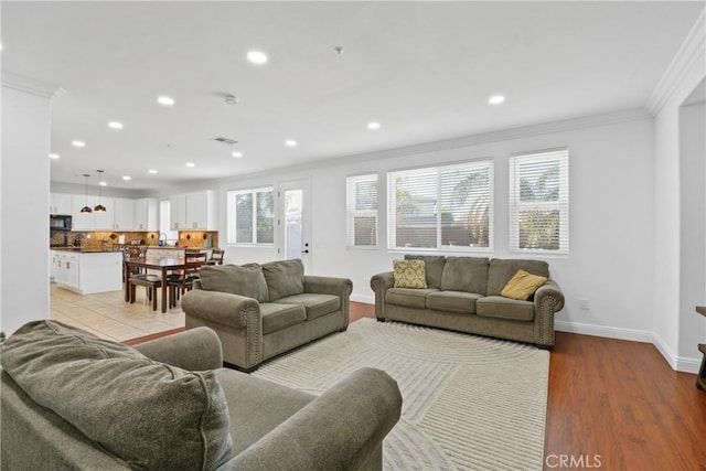 living room with a healthy amount of sunlight, light wood-type flooring, and ornamental molding