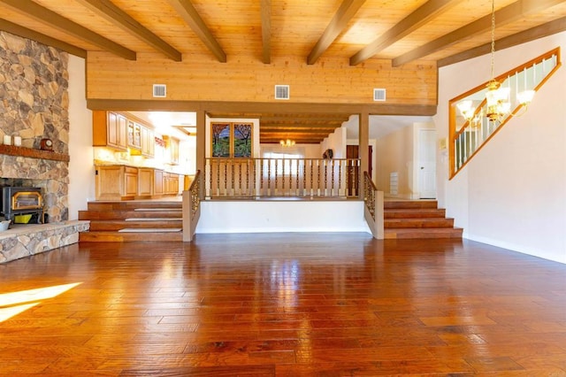 unfurnished living room featuring beam ceiling, a wood stove, wooden ceiling, a chandelier, and wood-type flooring