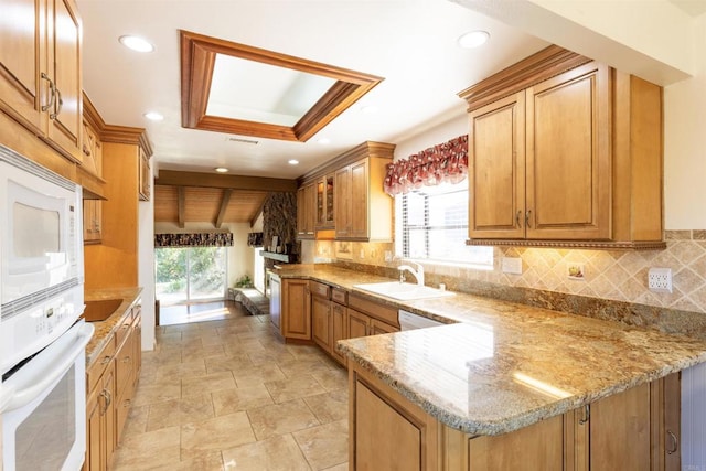 kitchen featuring sink, white appliances, kitchen peninsula, and a wealth of natural light