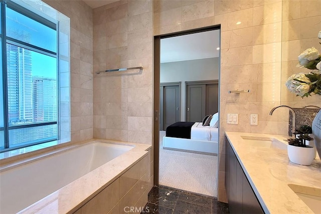 bathroom with plenty of natural light, tile walls, vanity, and tiled bath