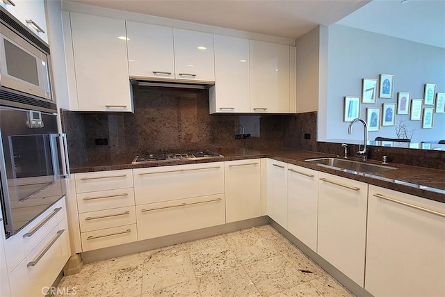 kitchen with backsplash, sink, dark stone countertops, appliances with stainless steel finishes, and white cabinetry