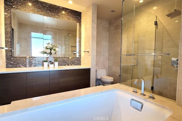 full bathroom with vanity, separate shower and tub, toilet, and tile walls