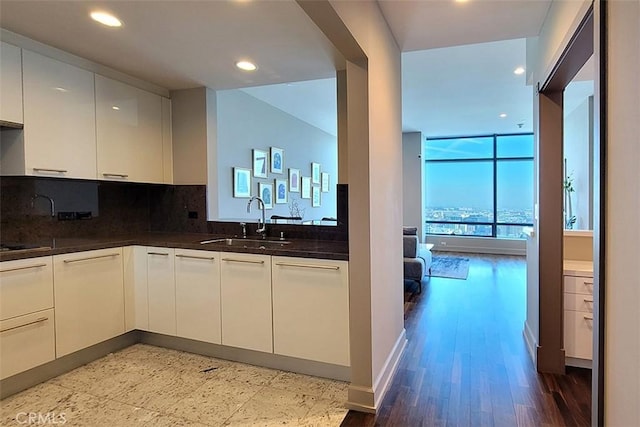 kitchen with white cabinets, sink, hardwood / wood-style flooring, dark stone countertops, and tasteful backsplash