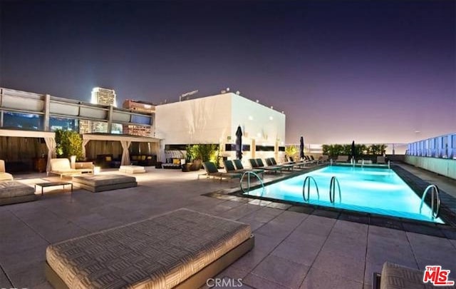 pool at dusk featuring a patio