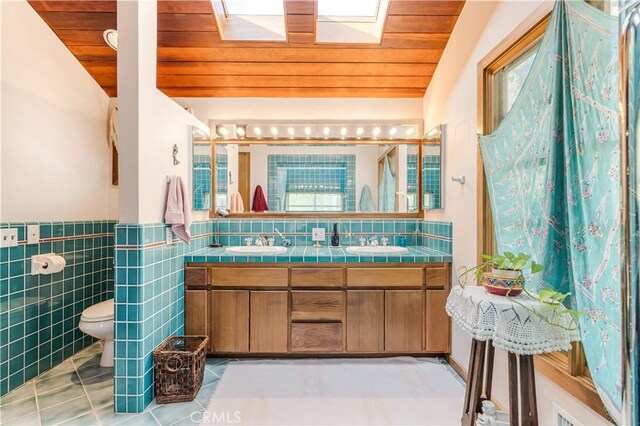 bathroom featuring wood ceiling, vaulted ceiling with skylight, tile patterned flooring, and tile walls