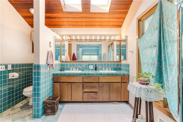 bathroom featuring vaulted ceiling with skylight, toilet, tile patterned floors, and wooden ceiling