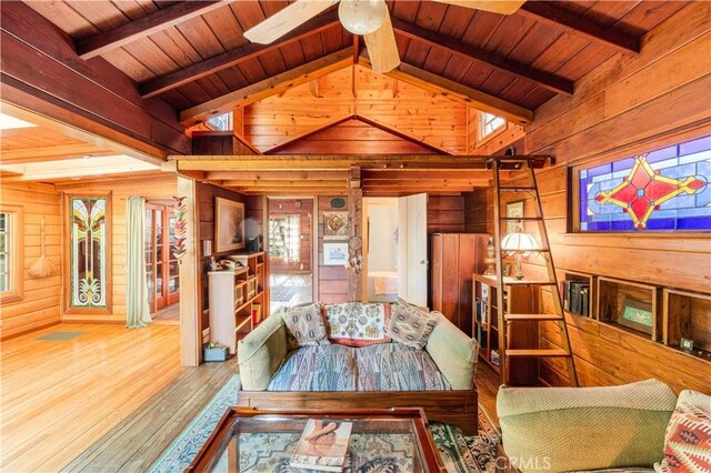 living room with vaulted ceiling with beams, wood ceiling, and wood walls