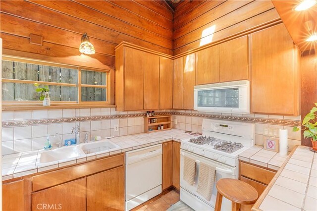 kitchen featuring sink, light tile patterned floors, white appliances, tile counters, and decorative backsplash