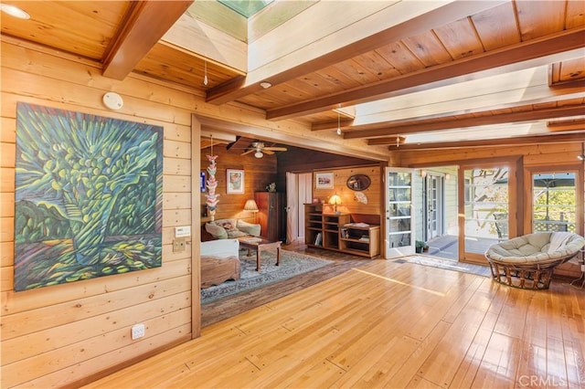 unfurnished room with beamed ceiling, wooden walls, a skylight, and hardwood / wood-style flooring