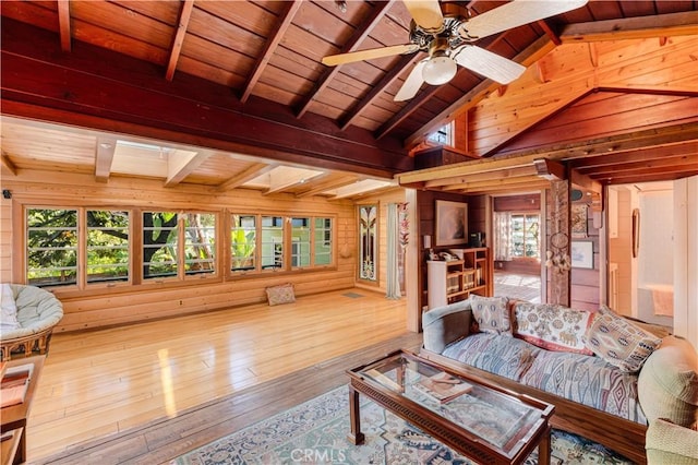 living room featuring lofted ceiling with skylight, wooden walls, hardwood / wood-style flooring, ceiling fan, and wood ceiling