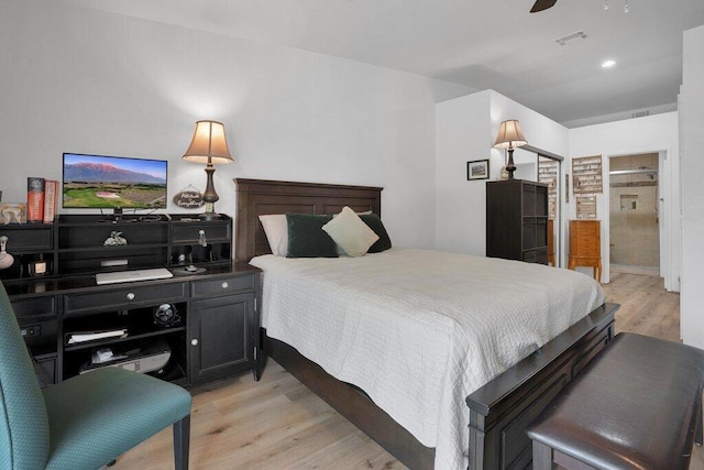 bedroom featuring ceiling fan, ensuite bathroom, and light wood-type flooring