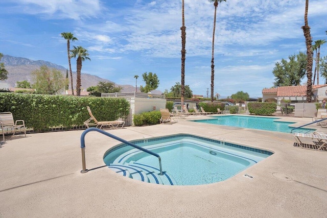 view of swimming pool featuring a mountain view, a community hot tub, and a patio