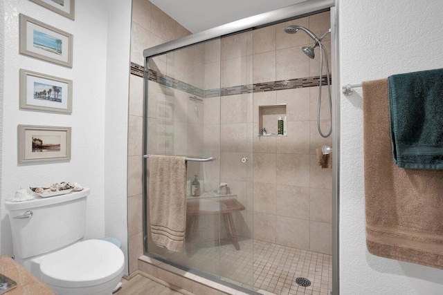 bathroom featuring toilet and a shower with shower door