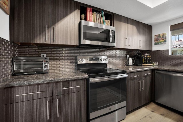 kitchen with dark stone countertops, decorative backsplash, and appliances with stainless steel finishes