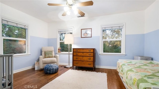 bedroom featuring multiple windows, dark wood-type flooring, and ceiling fan