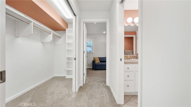 walk in closet featuring light colored carpet and sink