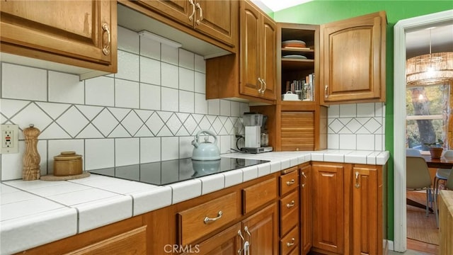 kitchen with tile countertops, decorative backsplash, black electric cooktop, and wood-type flooring