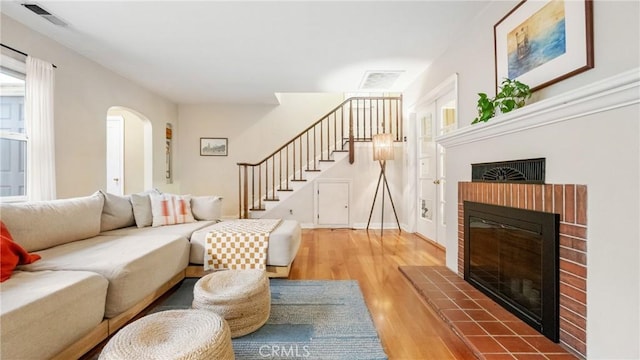 living room with wood-type flooring and a brick fireplace