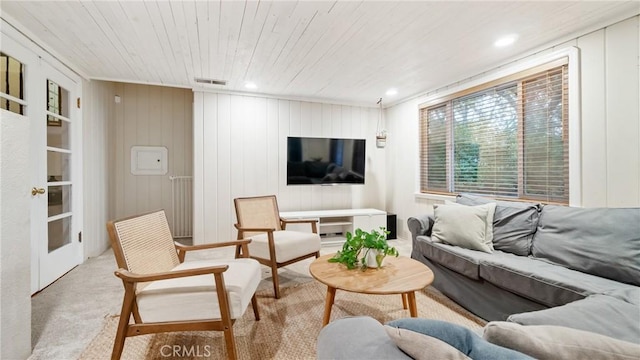 carpeted living room with wooden ceiling and wooden walls