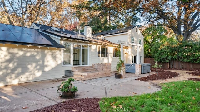 back of property with a patio and solar panels