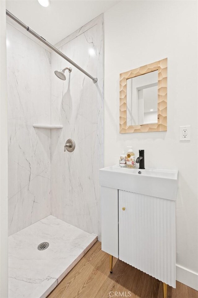 bathroom featuring hardwood / wood-style floors, vanity, and a tile shower