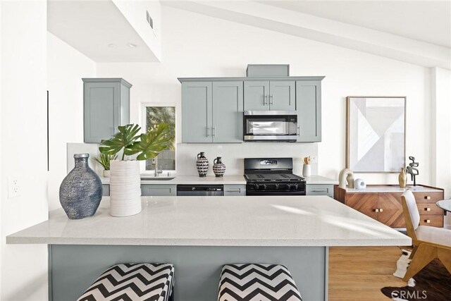 kitchen with kitchen peninsula, a kitchen breakfast bar, stainless steel appliances, and lofted ceiling