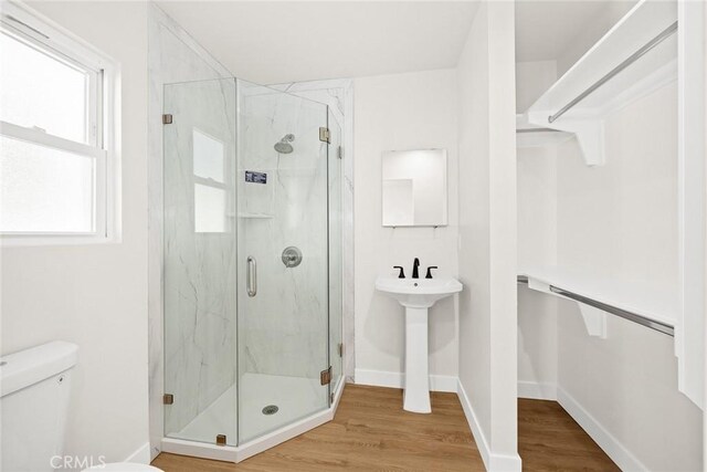 bathroom with toilet, wood-type flooring, and walk in shower