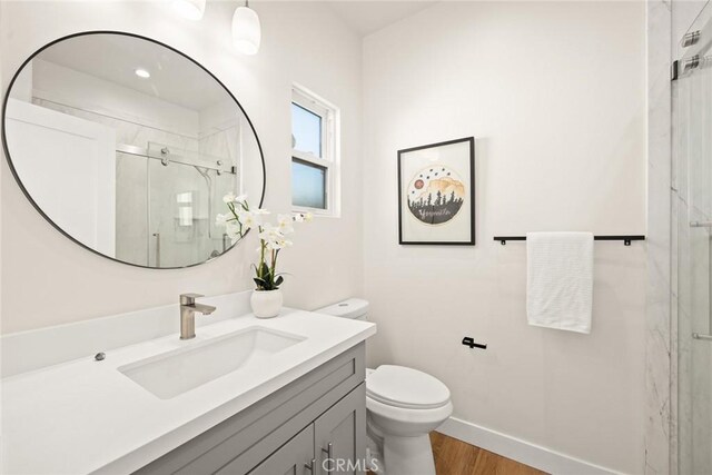 bathroom with hardwood / wood-style floors, vanity, an enclosed shower, and toilet