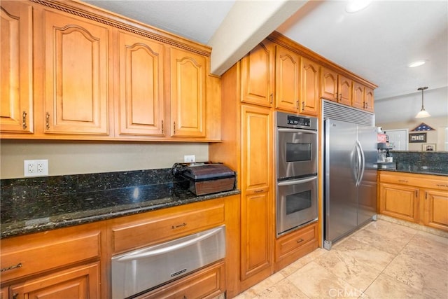 kitchen featuring pendant lighting, stainless steel appliances, and dark stone counters