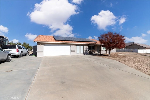 ranch-style house featuring a garage and solar panels