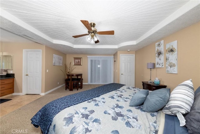 carpeted bedroom with a raised ceiling and ceiling fan