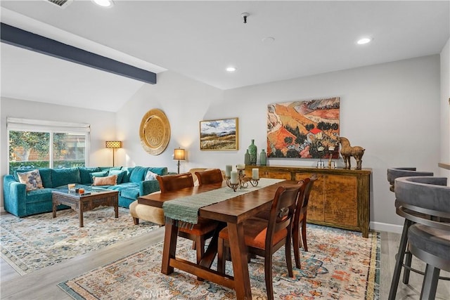 dining room featuring vaulted ceiling with beams and light hardwood / wood-style floors