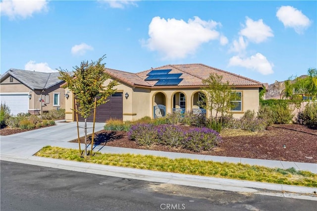 mediterranean / spanish-style house with a garage, covered porch, and solar panels