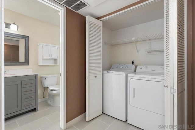 washroom with washer and dryer, light tile patterned floors, and sink