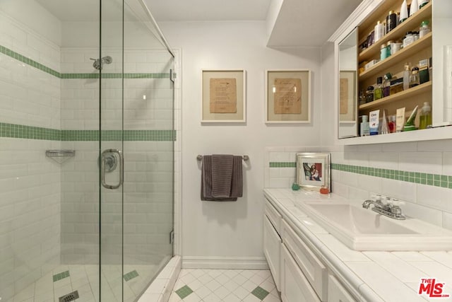 bathroom featuring backsplash, tile patterned flooring, vanity, and walk in shower