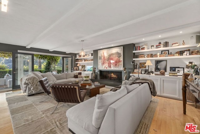 living room featuring beamed ceiling and light hardwood / wood-style floors