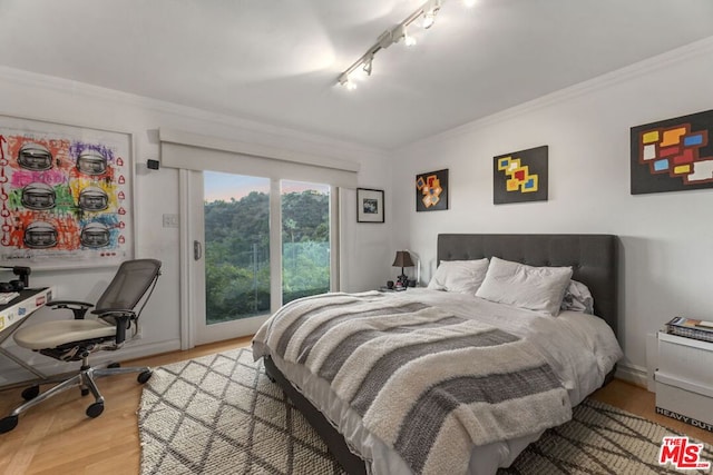 bedroom featuring hardwood / wood-style flooring, crown molding, and rail lighting