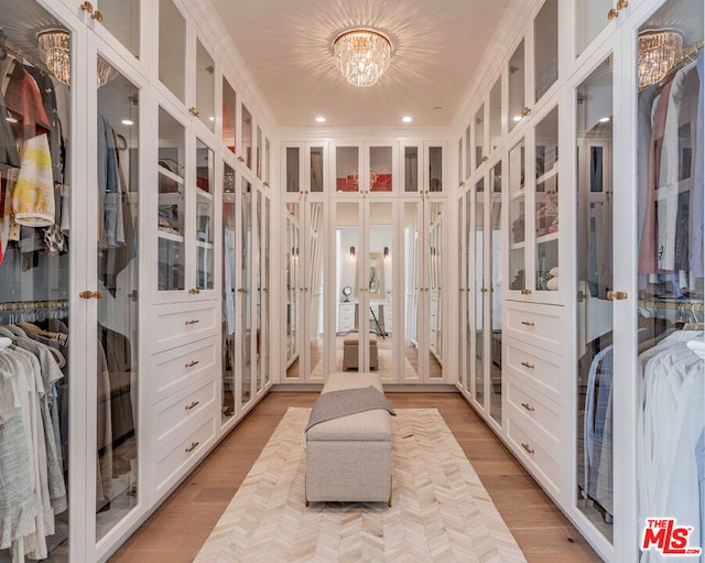 walk in closet with french doors, light hardwood / wood-style flooring, and a notable chandelier