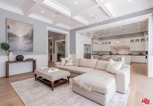 living room with beam ceiling, crown molding, light hardwood / wood-style floors, and coffered ceiling