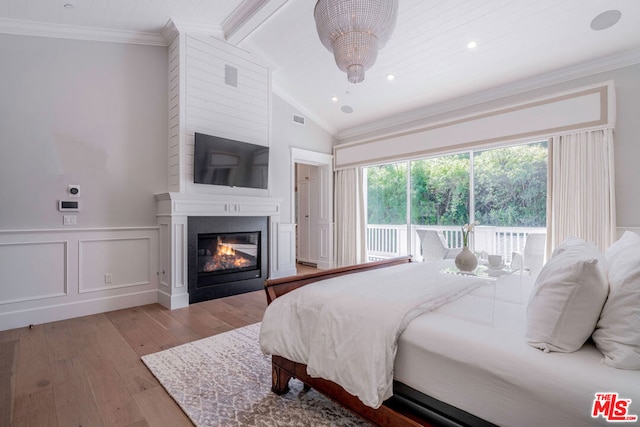 bedroom featuring crown molding, a large fireplace, lofted ceiling with beams, and light wood-type flooring