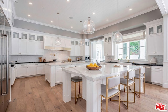 kitchen featuring a center island, dark stone counters, a kitchen breakfast bar, light hardwood / wood-style flooring, and decorative light fixtures