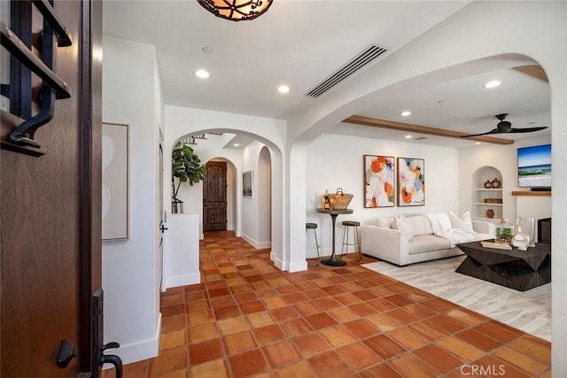 tiled living room featuring built in features and ceiling fan